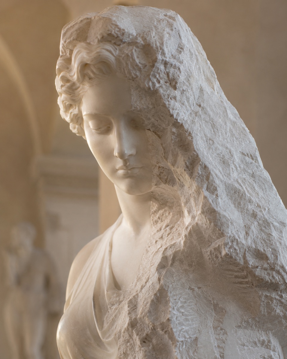A figure emerging from rough-hewn marble — the form revealed by removing the stone around it